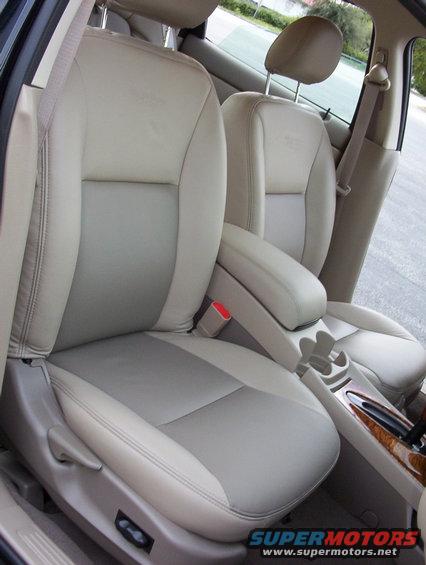 Front seats of a car, two-tone beige and gray upholstery, center console with cup holders