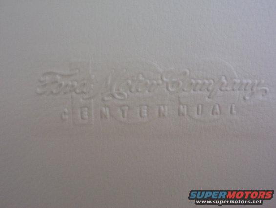 Embossed text reading "Ford Motor Company CENTENNIAL" on a light-colored surface