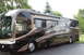 2003 Ford F-350 - This motorhome features a distinctive brown, beige, and black wavy stripe paint scheme, viewed from its side.