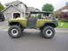 1974 Ford Bronco - A modified 1974 Ford Bronco sits on a suburban street, its lifted suspension and large tires prominent.
