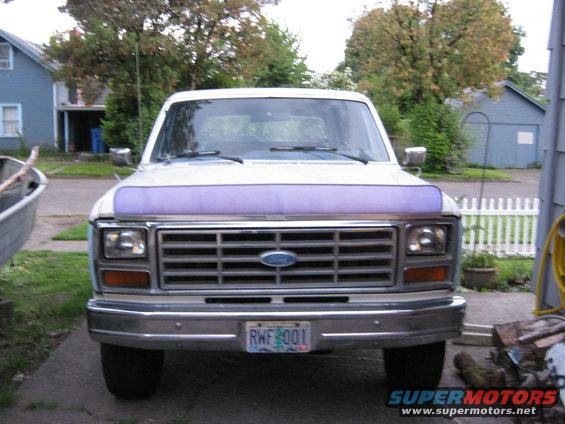 White Ford truck front view, purple hood protector, license plate RWF 001