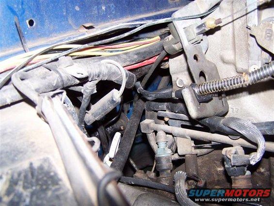 Close-up of engine bay wiring harness, cables, and sensors