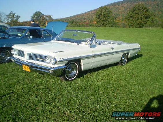 White convertible with chrome grille and trim, parked on grass