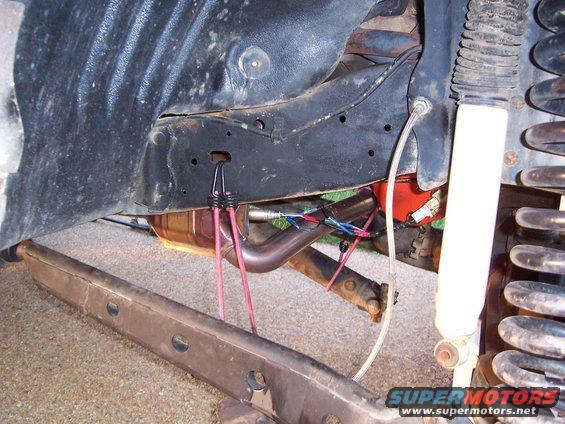 Undercarriage view showing exhaust pipe, suspension spring, shock absorber, and frame components