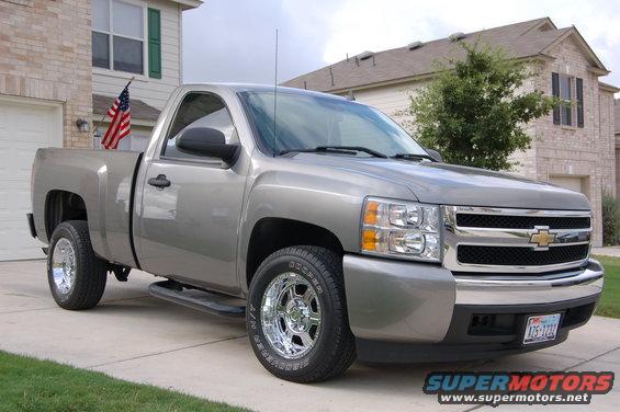 Silver pickup truck parked in driveway, American flag in bed