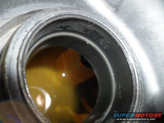 Close-up of an oil filler cap opening with yellow fluid visible inside