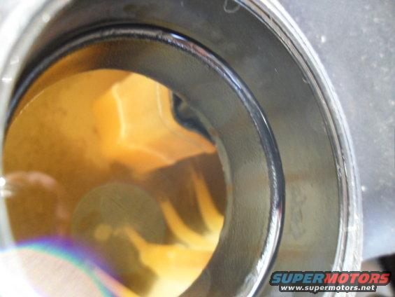 Close-up of an oil filter housing with yellow fluid inside