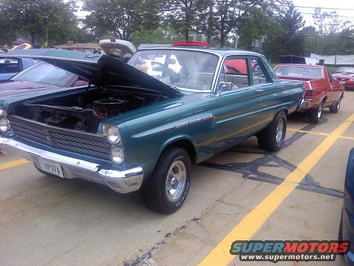 Teal 1964 Mercury Comet with hood open, parked next to a red car