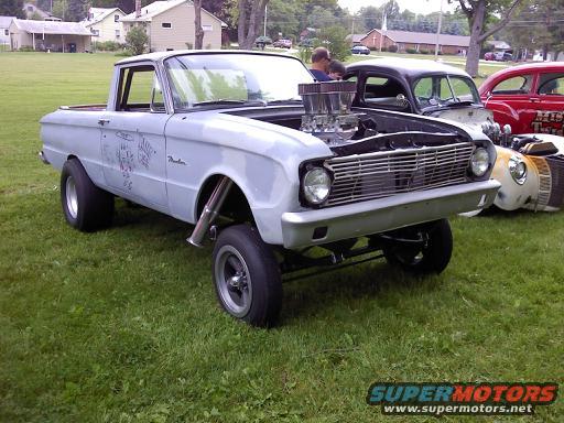 Customized 1960s pickup truck with large engine, side pipes, and drag slicks