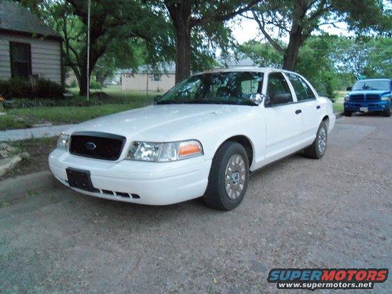 White sedan parked on street, blue truck in background