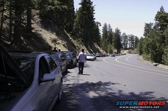 Silver sedan with hood open, parked cars on mountain road