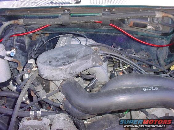 Engine bay with hoses, wiring, and intake manifold. Part number E8TE-9R504-A9 visible on a hose