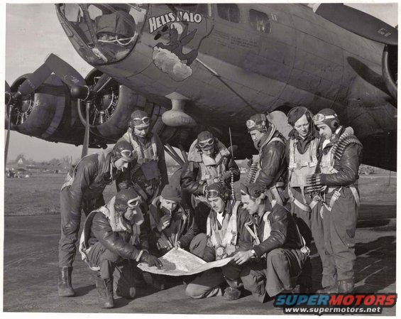 Bomber aircraft with nose art 'HELL'S ANGELS' and crew gathered around a map