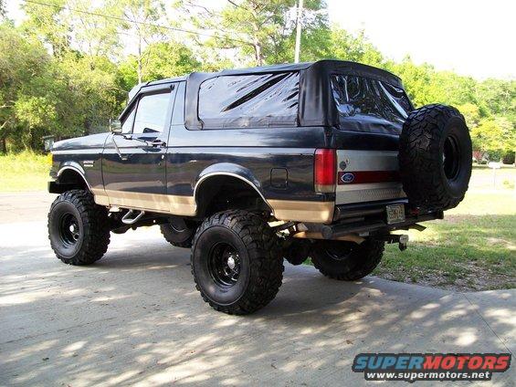 Lifted black Bronco with tan trim and soft top, rear spare tire