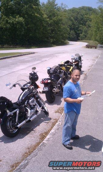 Motorcycles parked on roadside with a man holding papers