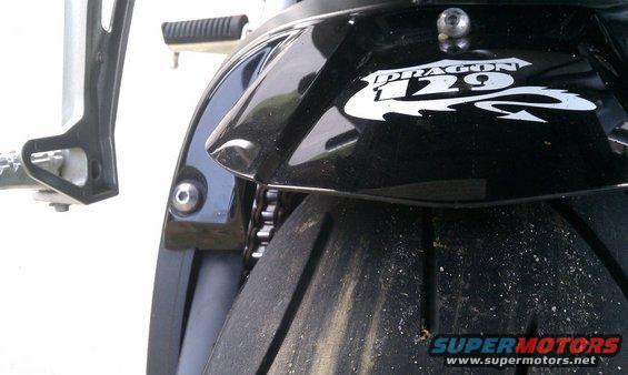 Black motorcycle rear fender with white 'DRAGON 129' graphic and tire. Supermotors.net logo visible