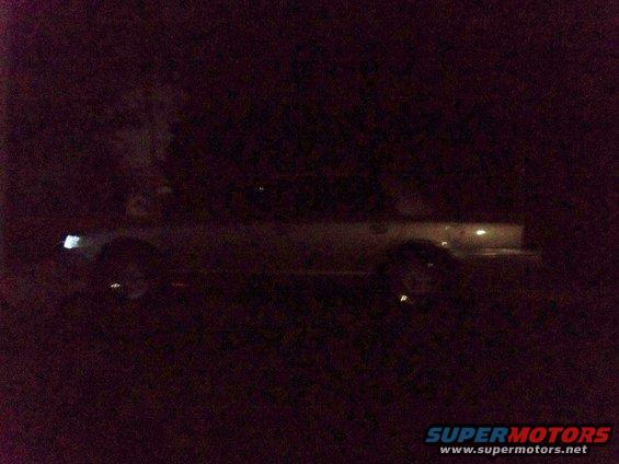 Side view of a sedan at night, headlights on