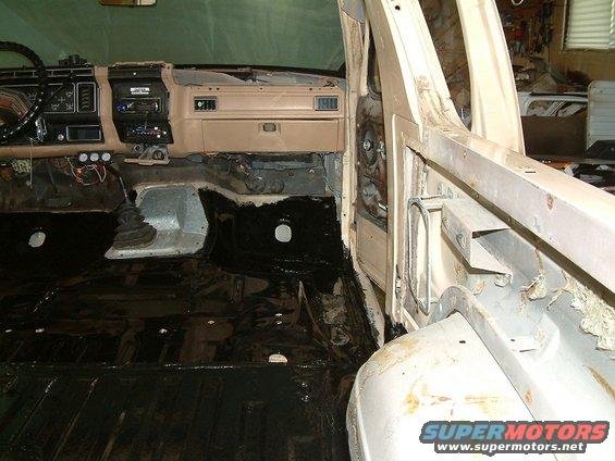Tan dashboard and black floor of a disassembled vehicle interior. A floor shifter is visible