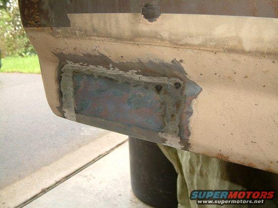 close-up of a metal patch welded onto a vehicle's body panel, showing repair work