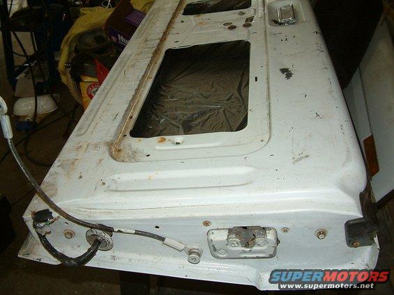 White tailgate with two window openings, showing rust and wear