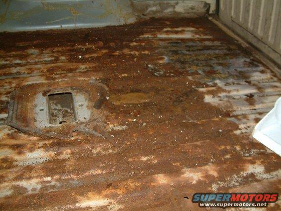 rusted out floor of a vehicle, looks like a truck bed or cargo area