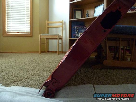 Red painted car part, possibly a fender or bumper, lying on a white cloth on a carpeted floor