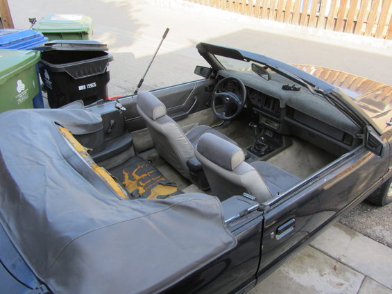 1985 Ford Mustang convertible interior showing torn seats and dashboard