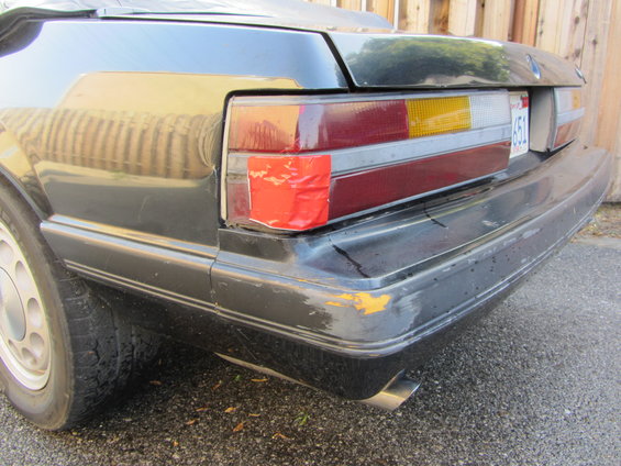 Rear bumper and taillight of a 1985 Ford Mustang with red tape on the taillight