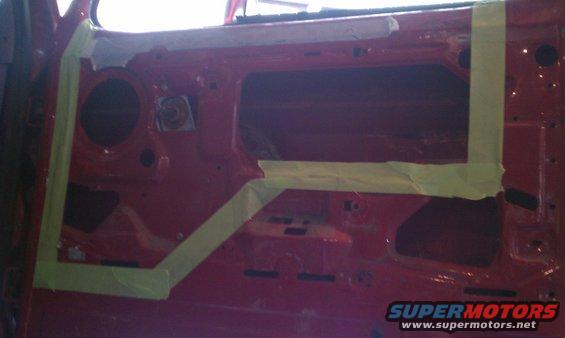 Red car door interior with masking tape applied to prepare for painting