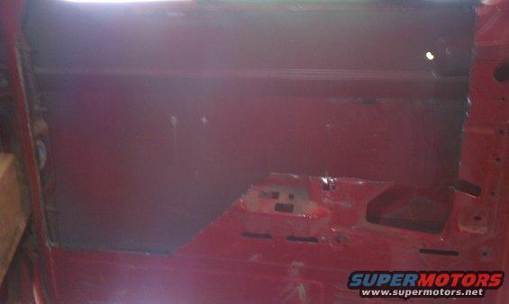 red interior door panel of a vehicle, showing bare metal and some mounting points