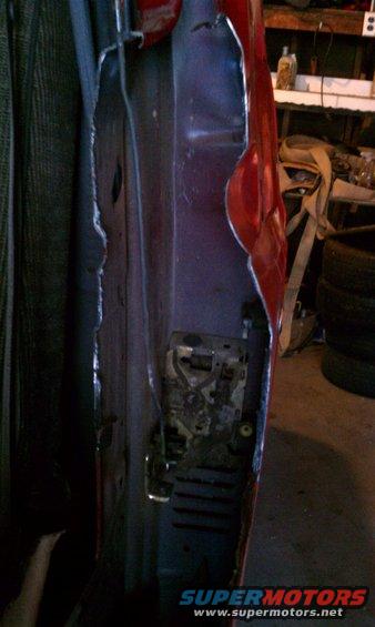 Red vehicle door interior with exposed latch mechanism and torn metal