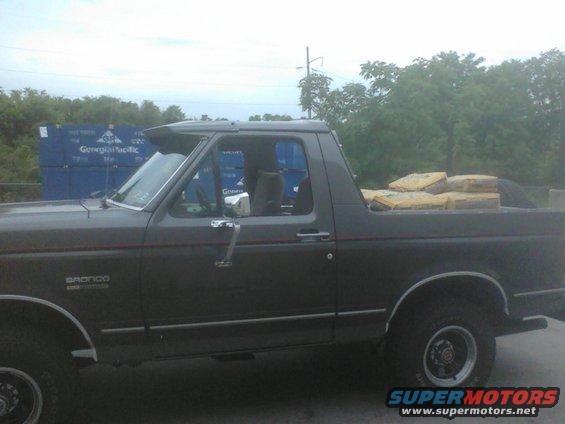 Dark gray Ford Bronco side view, carrying bags of cement in the bed