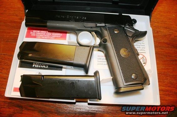 Black pistol with two magazines in a white case. Text on instructions and case