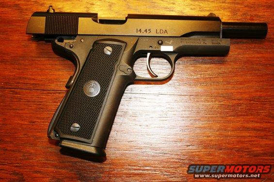 Pistol with "14.45 LDA" marking on slide, resting on wood surface
