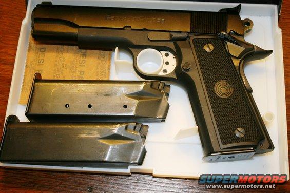 Black handgun with two magazines and sandpaper in a white box