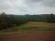 1989 Ford Bronco - A wide view of a rural landscape rolling hills, dense trees, and a field under an overcast sky.