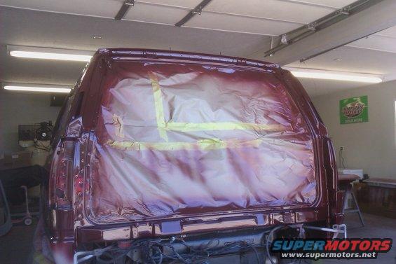 Rear of a red SUV with its windows taped off for painting