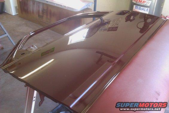 Brown car door on a stand, reflecting shop lights and equipment
