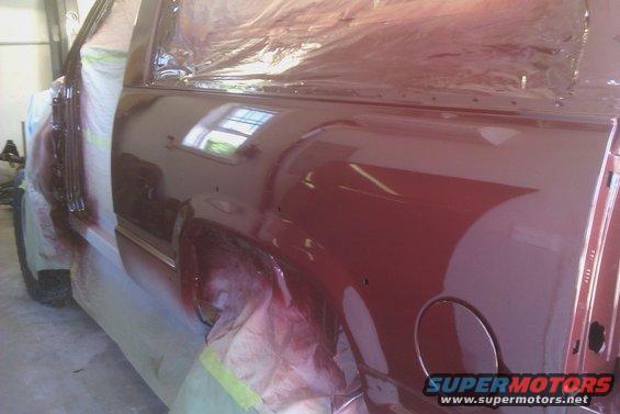 side view of a vehicle with fresh red paint, masked off for spraying