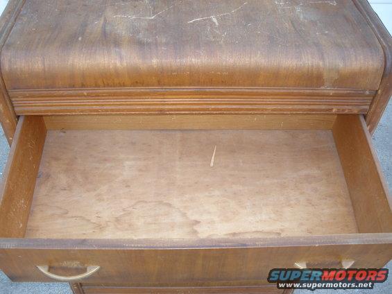 Wooden dresser drawer with brass handle, showing wear and scratches on the surface