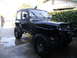 1992 Jeep Wrangler - This black Jeep Wrangler features large off-road tires and a custom front bumper, suggesting it's modified for off-roading.