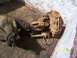 1989 Ford Bronco - A close-up view of a heavily rusted axle assembly, including a brake caliper, resting on a wooden surface.
