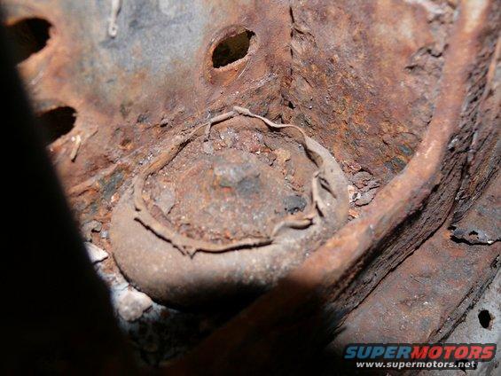 Close-up of heavily rusted metal frame part with a bolt head visible