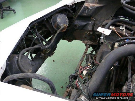 Car engine bay with hoses, wires, and engine components visible