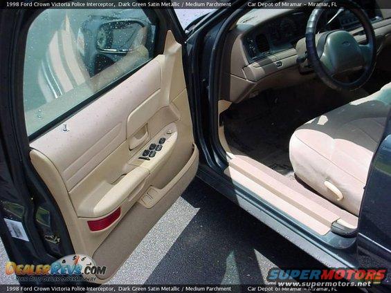 Interior of a 1998 Ford Crown Victoria police interceptor, showing the driver's side door open, dashboard, steering wheel, and front seat