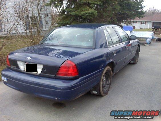 Dark blue sedan parked in a driveway. Rear view shows taillights and trunk