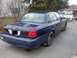 2002 Ford Crown Victoria - This sedan is parked outside a house with trees and other vehicles in the background.