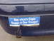 2002 Ford Crown Victoria - A close-up of a damaged bumper sticker on a dark blue vehicle reads "America's Cops Support Our Troops!"