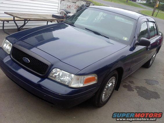 Dark blue 2002 Ford Crown Victoria, front 3/4 view, parked outdoors near a picnic table