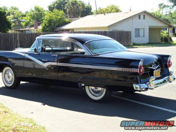 Black 1956 Ford Fairlane with chrome trim and whitewall tires parked on asphalt